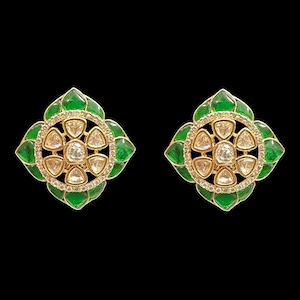 Puede incluir: Un par de pendientes de botón dorados con un diseño floral. Cada pendiente presenta un grupo central de piedras transparentes rodeado por un anillo de piedras transparentes más pequeñas y pétalos de esmalte verde. El fondo es negro.