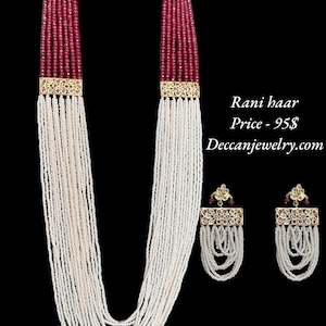 May include: An elegant necklace and earring set. The necklace features strands of white beads and burgundy beads, with gold-colored accents. The earrings have a similar design. The text "Rani haar" is visible.
