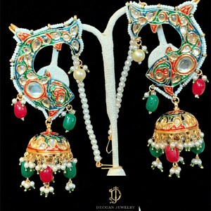 Puede incluir: Un par de pendientes de oro con diseño de pez. Los peces están decorados con esmalte de colores y piedras preciosas. Los pendientes cuelgan de una cadena de perlas.