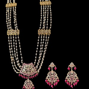 Pode incluir: Um colar de ouro com várias fileiras de pérolas e um pingente rosa e branco. Brincos combinando com pedras rosa e brancas.