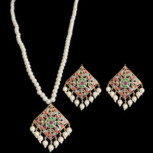 May include: A gold-toned jewelry set featuring a pendant necklace and matching earrings. The pendant and earrings have a diamond-shaped design with colorful gemstones and dangling white pearls. The necklace has a strand of white pearls.