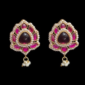 Pode incluir: Um par de brincos de ouro com pedras rosa e brancas. Os brincos têm um design floral e uma pérola pendurada.