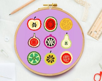 May include: A purple embroidery hoop with a cross-stitch design of various fruits, including a watermelon, apple, pear, fig, and orange. The fruits are all cut in half and show their insides.