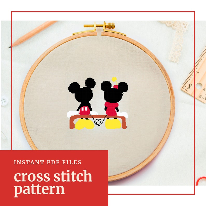 Op de afbeelding: Kruissteekpatroon met Mickey en Minnie Mouse die op een bankje zitten en elkaars hand vasthouden. Het patroon wordt getoond in een houten borduurring.