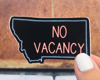Puede incluir: Una pegatina negra y blanca con forma del estado de Montana con las palabras "NO VACANCY" en letras rojas de neón.