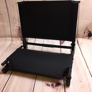 Puede incluir: Una silla plegable negra con asiento y respaldo acolchados. La silla est&aacute; hecha de metal y tela.