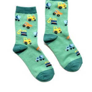 May include: A pair of green socks with a pattern of yellow construction vehicles. The socks have a dark green cuff.