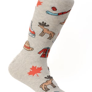 May include: A pair of gray socks with a Canadian theme. The socks feature images of a moose, a maple leaf, a hockey stick, a toque, and a winter jacket.