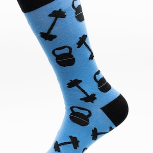 May include: A pair of blue socks with a black and white pattern of dumbbells and kettlebells.