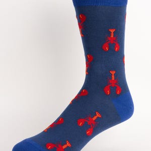 May include: A navy blue sock featuring a repeating pattern of red lobsters. The toe, heel, and cuff are solid blue. The socks are made of a soft, comfortable material.