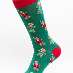 Könnte beinhalten: Grüne Socken mit rotem Bündchen und einem Muster aus Lebkuchenmännern, die Weihnachtsmannmützen und Elfenkostüme tragen.