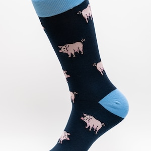 May include: Navy blue socks with a light blue cuff, heel, and toe. The socks are patterned with pink pigs. The socks are made of a soft, comfortable material.