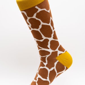 May include: A pair of brown and white giraffe print socks with a yellow cuff.