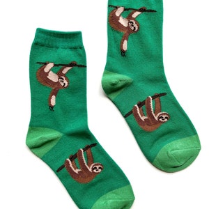 May include: A pair of green socks with a brown sloth hanging from a branch on each sock.