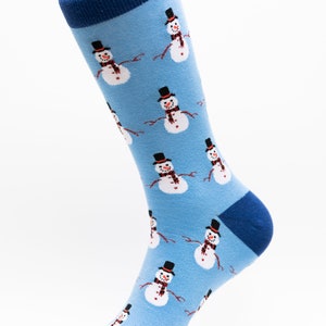May include: A pair of blue socks with a pattern of white snowmen wearing black top hats and red scarves.