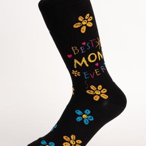 May include: Black sock with the text "Best Mom Ever" in colorful letters, decorated with yellow and blue flowers. The sock is knee-high and has a white cuff.
