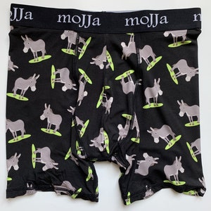以下が含まれることがあります： 黒いボクサーパンツ。緑のサーフボードに乗った灰色のロバの繰り返し模様。黒いウエストバンドには白い文字で「mojja」とプリントされています。柔らかく快適な素材です。
