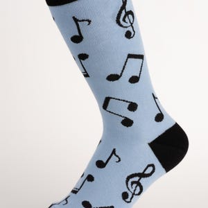 May include: A light blue sock with a black heel, toe, and cuff. The sock is patterned with black musical notes and treble clef symbols. The sock is made of a soft, comfortable material.