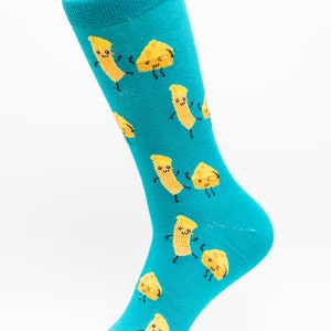 Könnte beinhalten: Ein Paar türkisblaue Socken mit einem Muster aus gelben lächelnden Käsescheiben und Makkaroni.