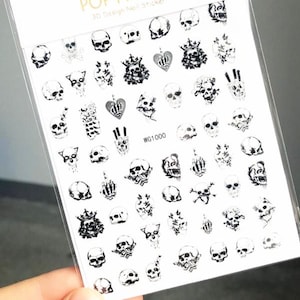 May include: A sheet of nail art stickers featuring various black and white skull designs. The stickers include skulls with crowns, hearts, and other gothic-inspired elements. The package is labeled "POP FINGER 3D Design Nail Sticker."