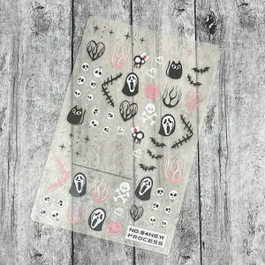 May include: A sheet of Halloween-themed nail art stickers. The stickers feature various designs, including ghosts, bats, skulls, hearts, and flames, in black, pink, and white. The text "NO.54NEW PROCESS" is printed on the bottom.