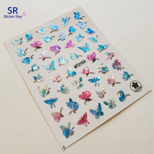 Op de afbeelding: Een vel vlinderstickers in verschillende kleuren, waaronder blauw, roze en iriserend. De stickers hebben een glinsterend, getextureerd uiterlijk en zijn gerangschikt op een witte achtergrond. De tekst "MT21SA" is zichtbaar.