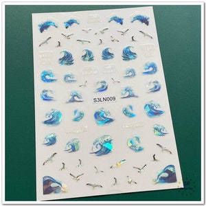 Può includere: Un foglio di adesivi a tema oceano con onde blu, gabbiani e le parole "Hello Sea", "Sea Wave" e "Seagull". Gli adesivi hanno un effetto olografico e il codice "S3LN009".