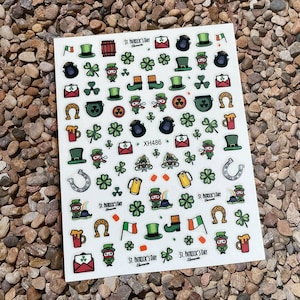 May include: A sheet of nail stickers with a St. Patrick's Day theme. The stickers feature various green shamrocks, leprechauns, pots of gold, and other festive imagery. The sheet also includes the text "St. Patrick's Day" and "XH486".