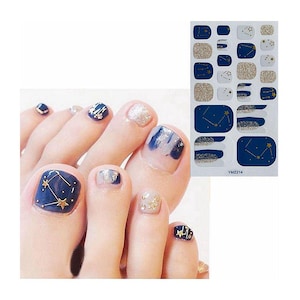 May include: Toe nail stickers with a constellation design in gold and blue on a white background. The stickers are shown on a model's toes.