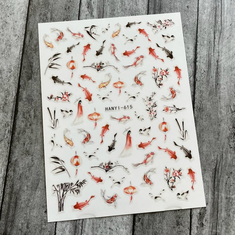 May include: A sheet of clear nail stickers with a variety of designs, including red and black koi fish, cherry blossoms, bamboo, and lanterns. The text "HANYI-615" is printed on the sheet.