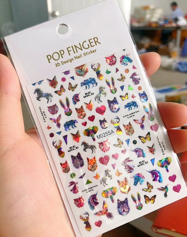 May include: A sheet of colorful nail stickers with a variety of designs, including animals, hearts, and geometric shapes. The stickers are holographic and have a rainbow iridescent finish. The text "POP FINGER 3D Design Nail Sticker" and "M025SA" are printed on the sheet.