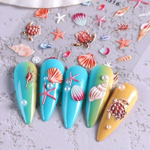 May include: Nail art design with sea-themed decorations. The nails are painted in blue, yellow, and green, with 3D embellishments of starfish, seashells, and turtles. Some nails have pearl accents.
