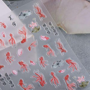 May include: Clear sheet of stickers featuring red koi fish, pink lotus flowers, and green lily pads. The stickers also include Chinese characters. The stickers are designed with a watercolor effect.