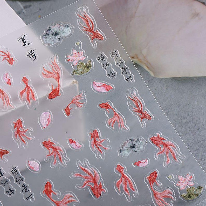 May include: Clear sheet of stickers featuring red koi fish, pink lotus flowers, and green lily pads. The stickers also include Chinese characters. The stickers are designed with a watercolor effect.