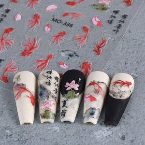 May include: Nail art stickers featuring red koi fish and floral designs. The stickers are on a clear sheet with the text "MO-336". Five painted nails showcase similar designs, including koi fish, lotus flowers, and Chinese calligraphy.