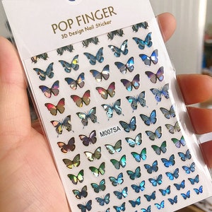 May include: A sheet of iridescent butterfly nail stickers. The stickers are arranged in rows and feature a variety of blue, green, and purple butterflies. The sheet is labeled "POP FINGER 3D Design Nail Sticker" and "M007SA".