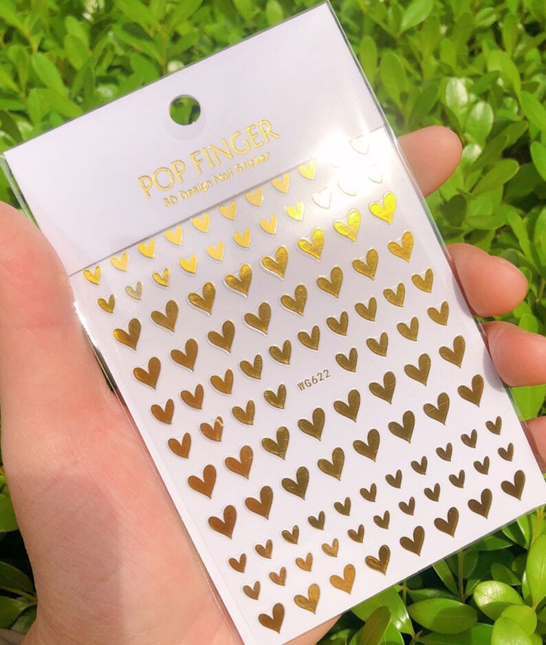 Op de afbeelding: Gouden hart nagelstickers op een wit vel met de tekst "POP FINGER 3D Design Nail Sticker" en "WG622".