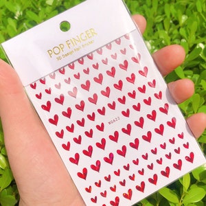 Op de afbeelding: Een vel met rode hartvormige nagelstickers met een holografische afwerking. Het vel is gelabeld met "POP FINGER 3D Design Nail Sticker" en "WG622".