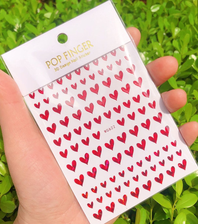Op de afbeelding: Een vel met rode hartvormige nagelstickers met een holografische afwerking. Het vel is gelabeld met "POP FINGER 3D Design Nail Sticker" en "WG622".