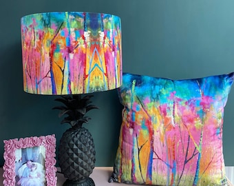 May include: A black pineapple lamp base with a colorful abstract lampshade. The lampshade features a design of trees and branches in shades of pink, blue, green, and yellow. A matching pillow with the same design is also shown.