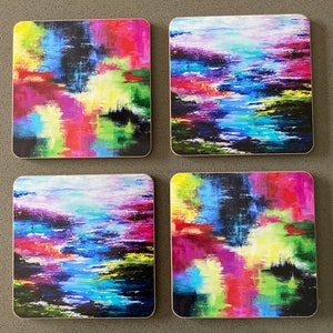 May include: Set of four square coasters with abstract colourful designs. The coasters feature a mix of bright colours, including pink, blue, green, yellow, and red, with a black background. The designs are reminiscent of water reflections or a sunset.