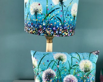 May include: A blue lampshade with a white dandelion design and a blue and white pillow with a dandelion design.