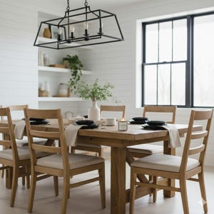 Modern farmhouse dining room with a wooden table and chairs, black metal chandelier overhead, and neutral table setting in a bright space
