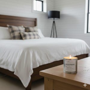 Mountainside wood wick candle burning on a bedside table, with a cozy bedroom featuring a wooden bed frame and neutral bedding