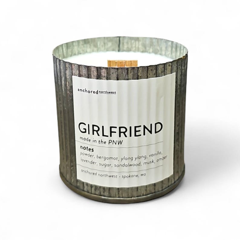 Girlfriend wood wick candle in rustic corrugated metal tin with white label, featuring notes of bergamot, vanilla, lavender, and sandalwood, made in the PNW.