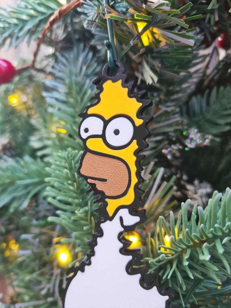 A funny 3D Printed Christmas tree decoration of Homer Simpson backing into bushes, hanging on a Christmas tree