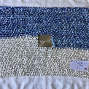 May include: A crocheted baby blanket in shades of blue and white. The blanket has a tag that reads "Baby Blues and White".