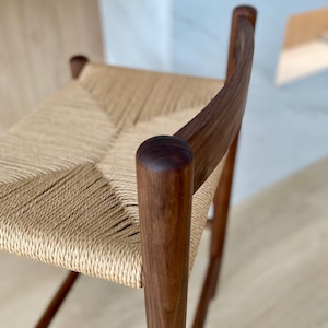 May include: A wooden chair with a woven cane seat. The chair is made of dark brown wood and has a simple, elegant design.