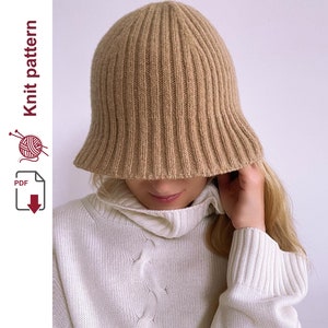 May include: A brown ribbed knit hat with a wide brim. The hat is being worn by a person, but only the top of the hat is visible.