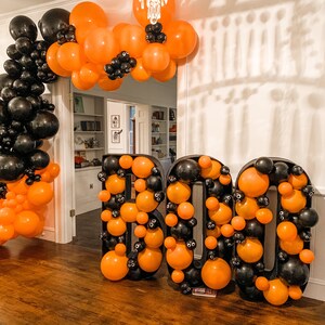 May include: A Halloween decoration made of black and orange balloons in the shape of the word "BOO".